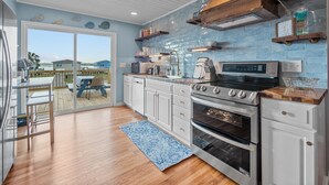 A modern kitchen with white cabinets, a stainless steel oven, and a blue backsplash.