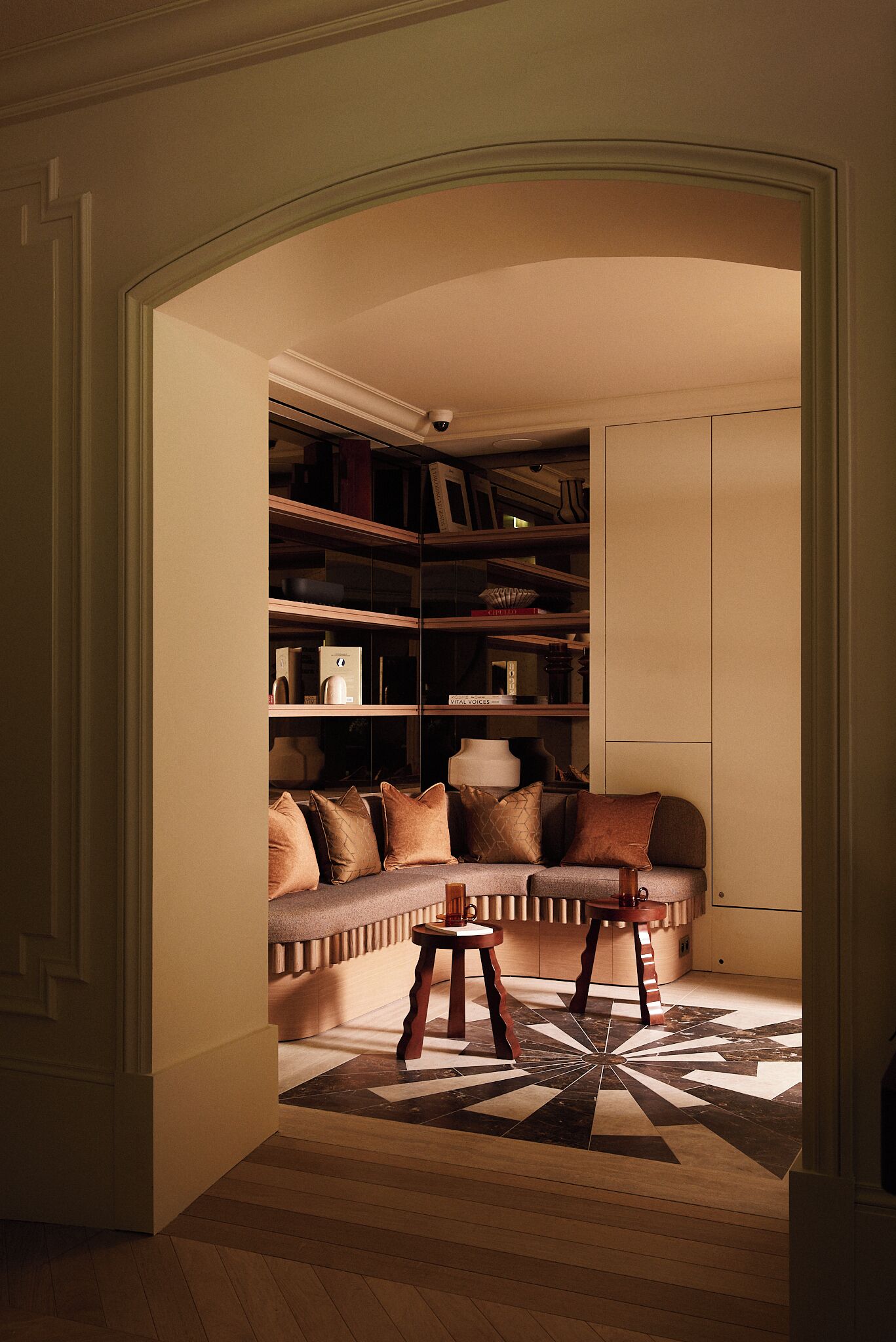 A cozy reading nook with a cushioned bench, a small wooden table, and a patterned rug.