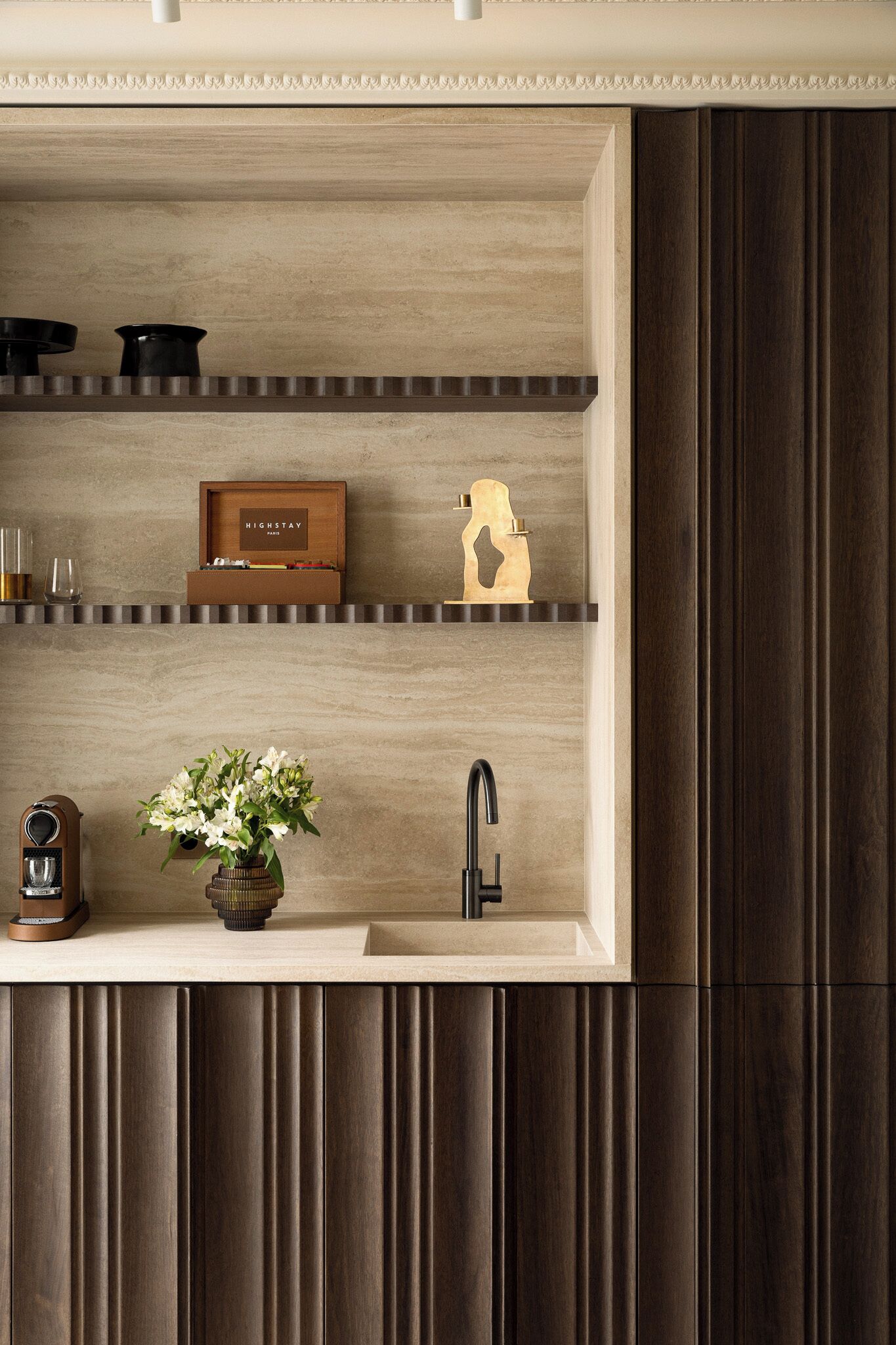 A kitchen with a wooden countertop, a sink, and a shelf with decorative items.