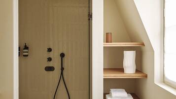 Een kleine, moderne badkamer met een douche, een handdoekrek en een plank met een handdoek.
