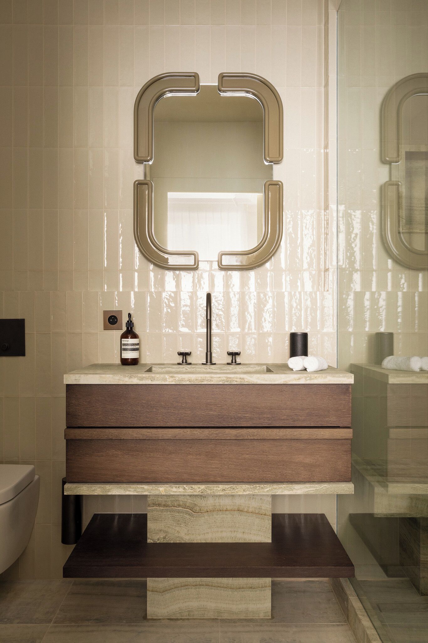 A modern bathroom with a large mirror, a wooden vanity, and a marble countertop.