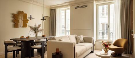 A modern living room with a sofa, coffee table, and dining table.