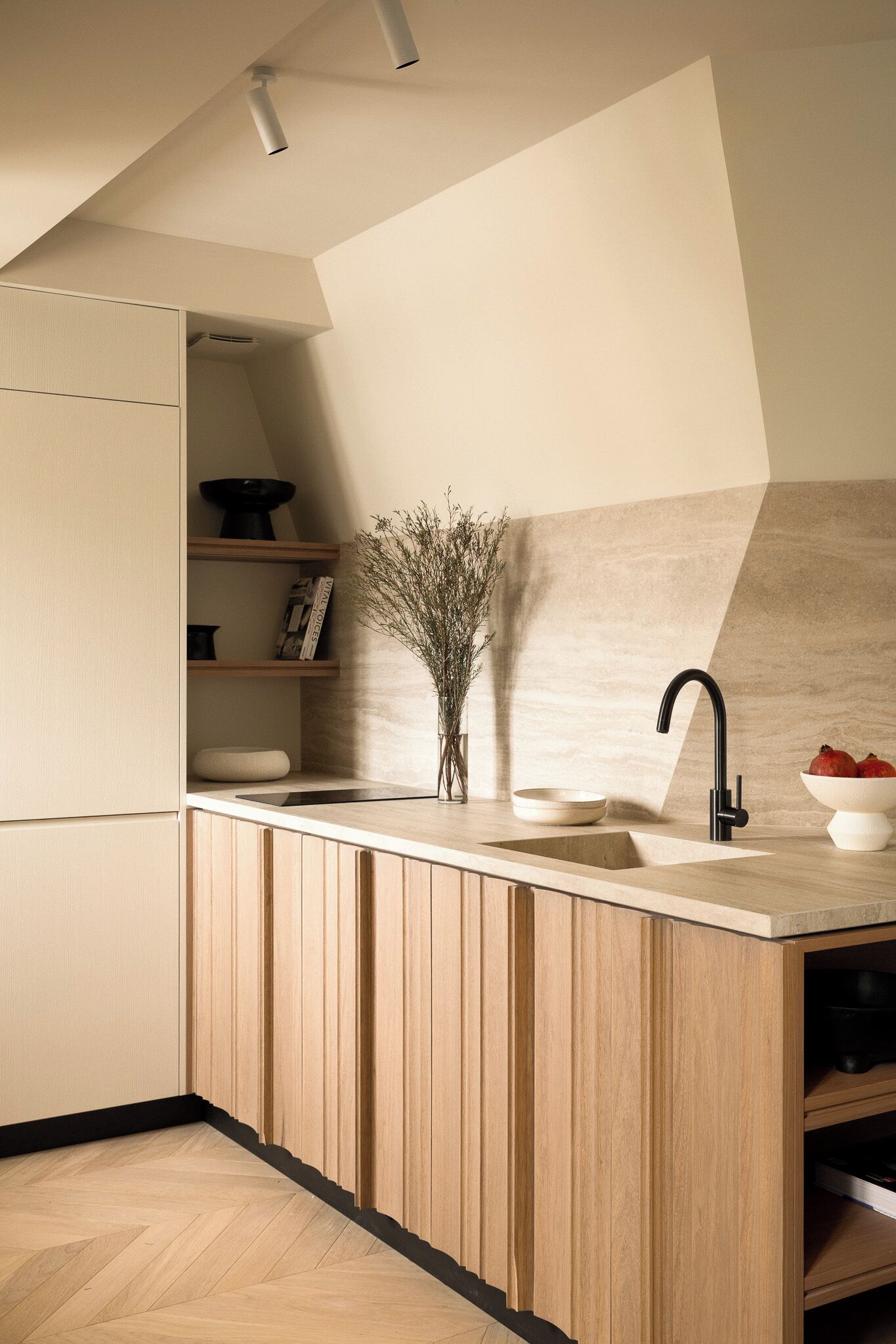 A modern kitchen with wooden cabinetry, a built-in sink, and a vase with dried flowers.