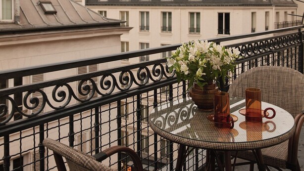 A balcony with wicker chairs and a table, overlooking a row of buildings with distinct architectural styles. - HIGHSTAY Maison - Boétie (Paris)
