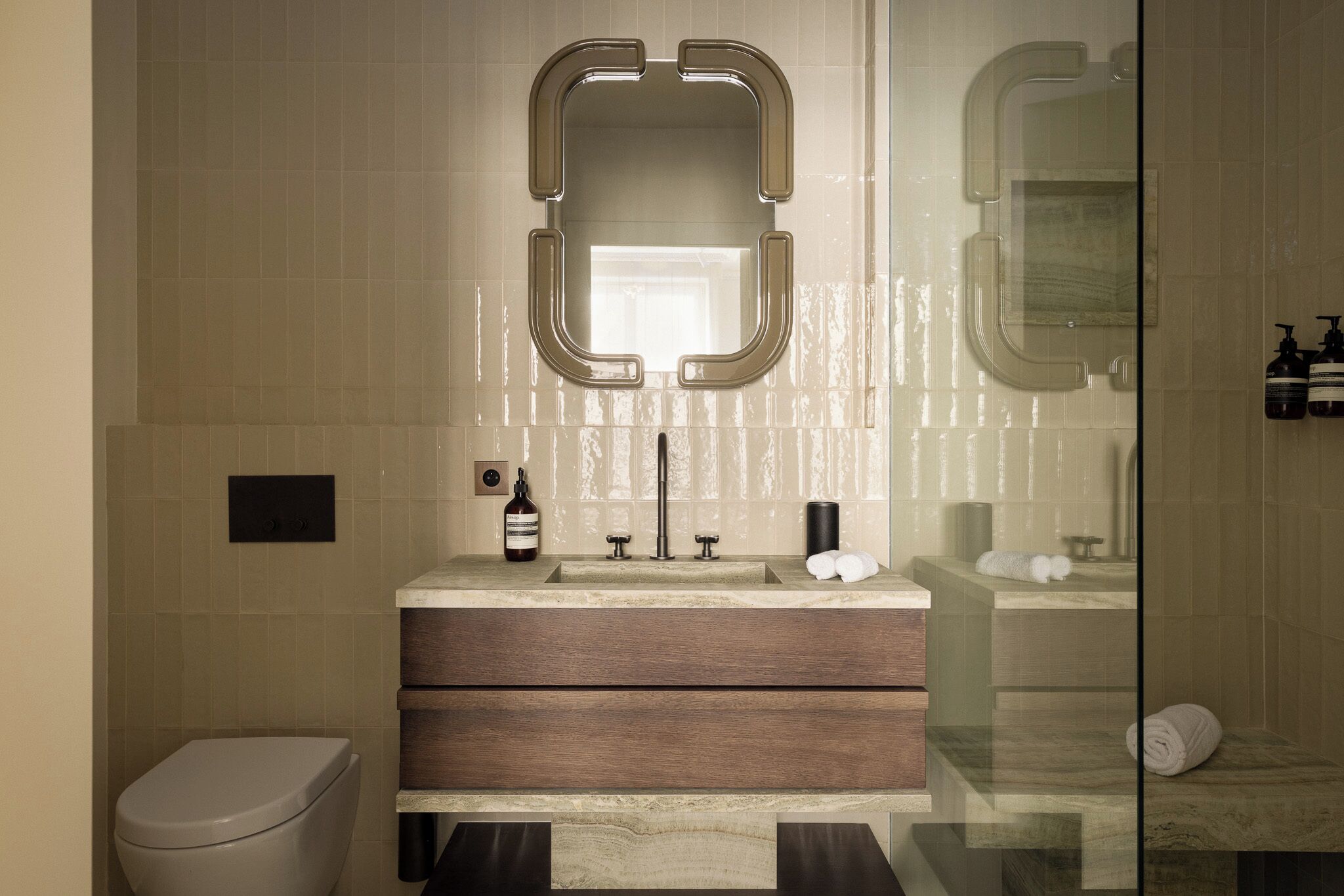 A modern bathroom with a large mirror, a sink with a wooden vanity, a toilet, and a glass shower enclosure.