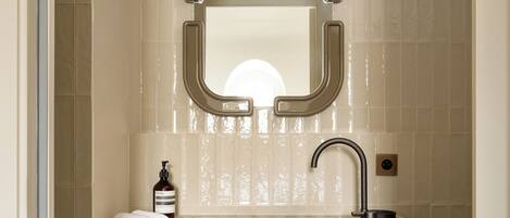 A modern bathroom with a large mirror, a sink, and a towel rack.