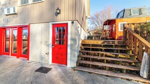 Un edificio con una puerta roja y una escalera que conduce a una terraza.