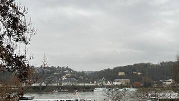 A riverside promenade with a view of a river, boats, and a distant cityscape.