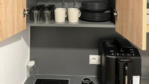 Una cucina compatta con mobili in legno, una macchina da caffè Bosch e un bollitore sul piano di lavoro.