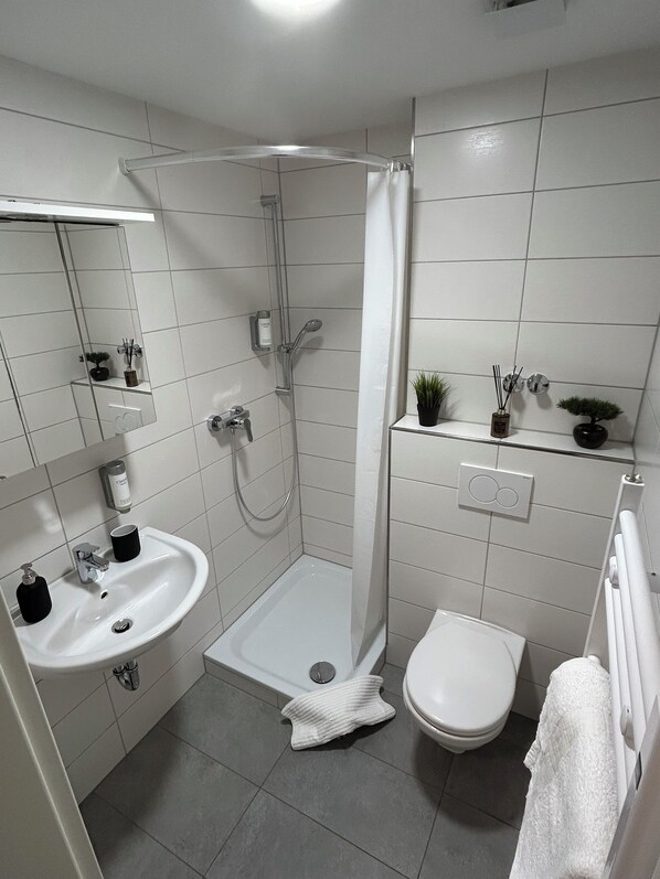 Une salle de bain moderne équipée d’une douche, de toilettes et d’un lavabo.