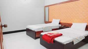 A hotel room with two single beds, a wooden headboard, and a white tiled floor.