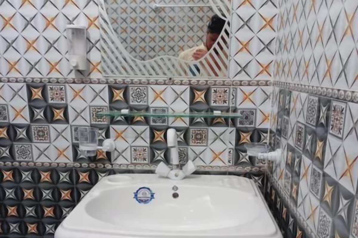 Un bagno con lavandino bianco, piastrelle decorate e uno specchio.