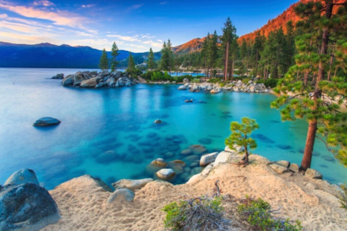 Ein klarer See mit sichtbaren Felsen und Bäumen.