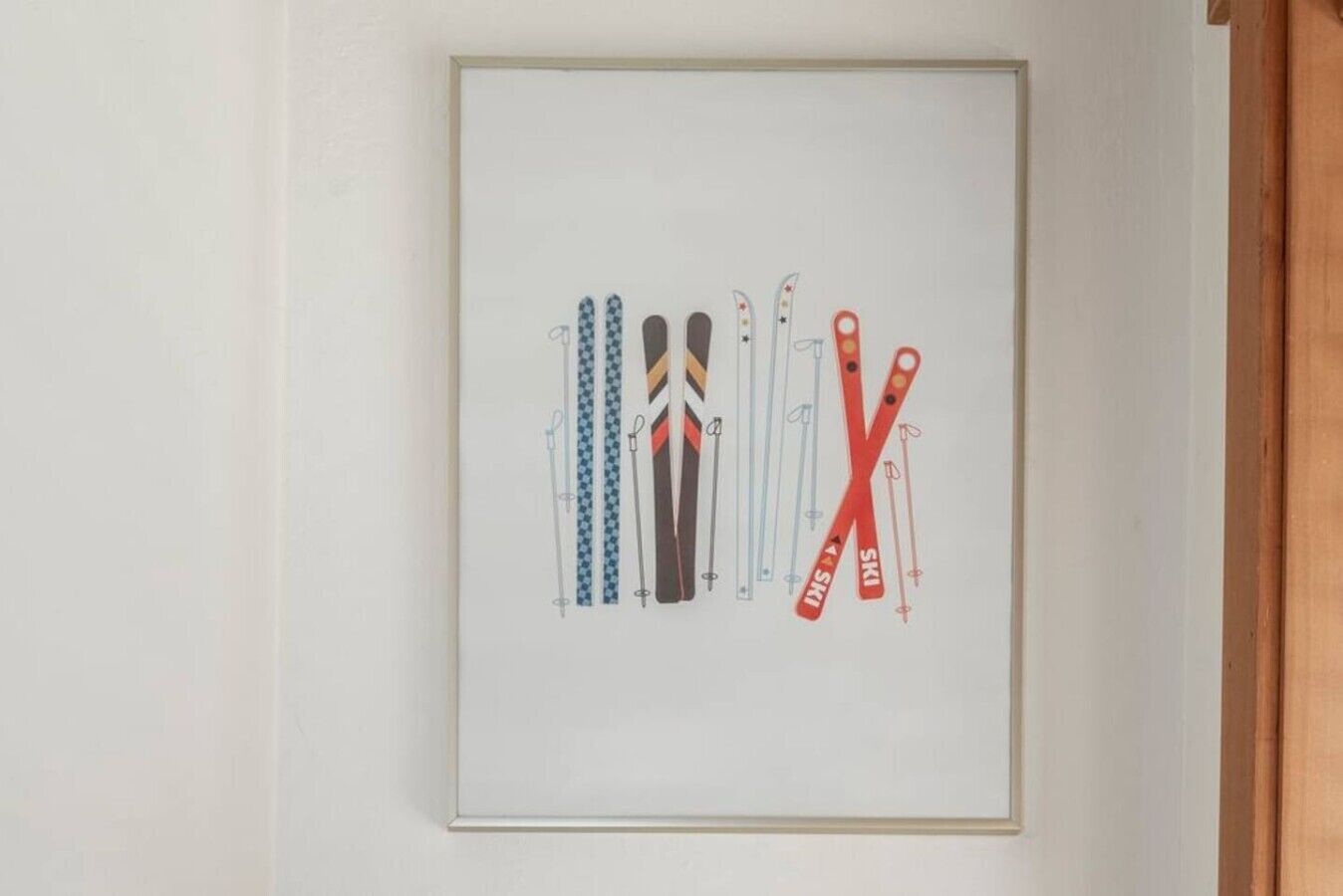 A framed picture of skis and ski poles on a wall.