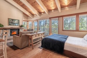 Une chambre avec une cheminée, un canapé, un lit et de grandes fenêtres.