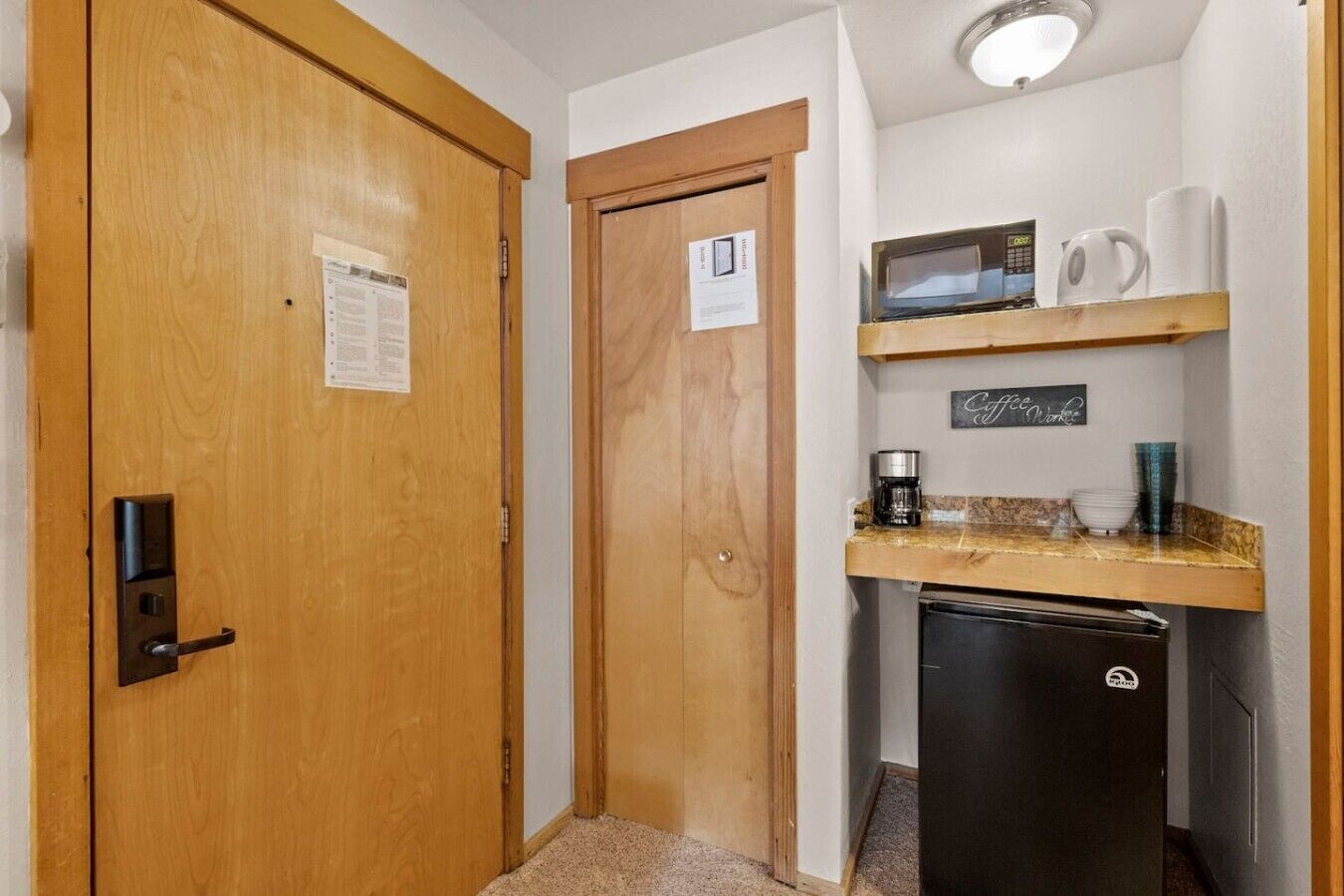 Cocina compacta con microondas, cafetera y un refrigerador pequeño.