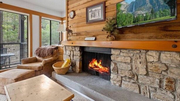 A cozy room with a stone fireplace, a mounted television, and a framed picture above the fireplace.