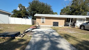 A residential driveway leading to a house with a garage, a covered porch, and a car parked in the driveway. - Neverland apartment (Jacksonville)