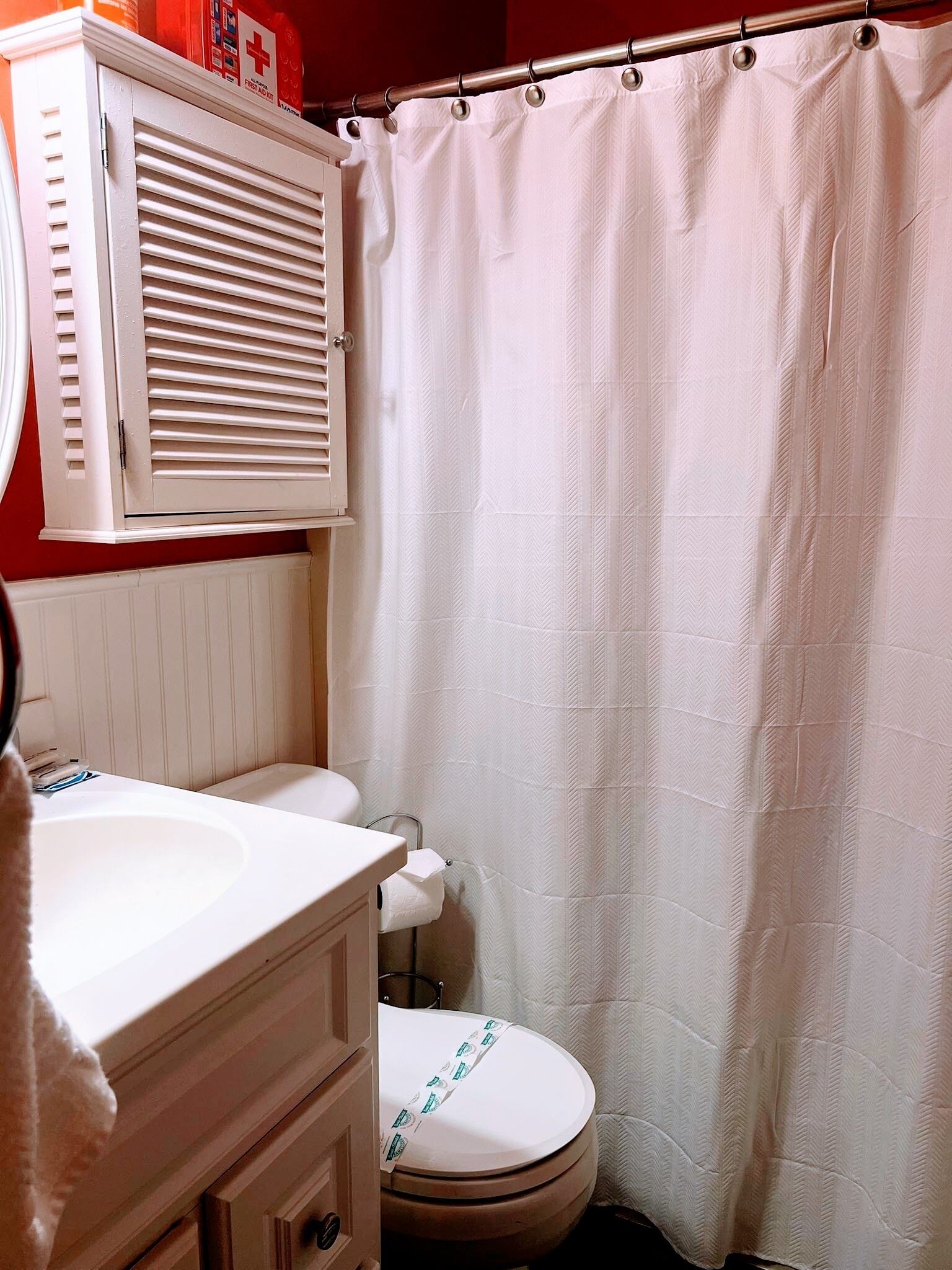A bathroom with a white sink, toilet, and shower curtain.