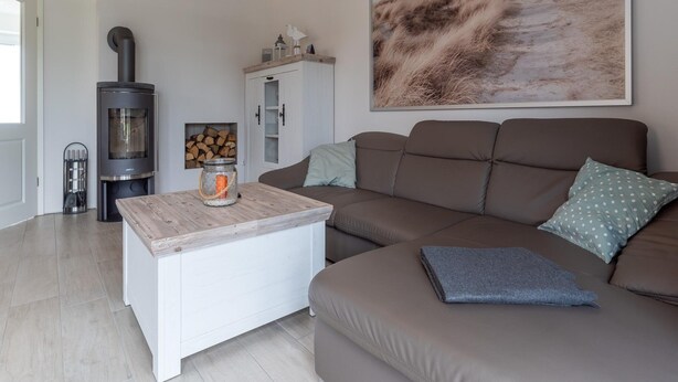 Una sala de estar moderna con un sofá, una mesa de centro, una chimenea y un cuadro de paisaje de gran tamaño.