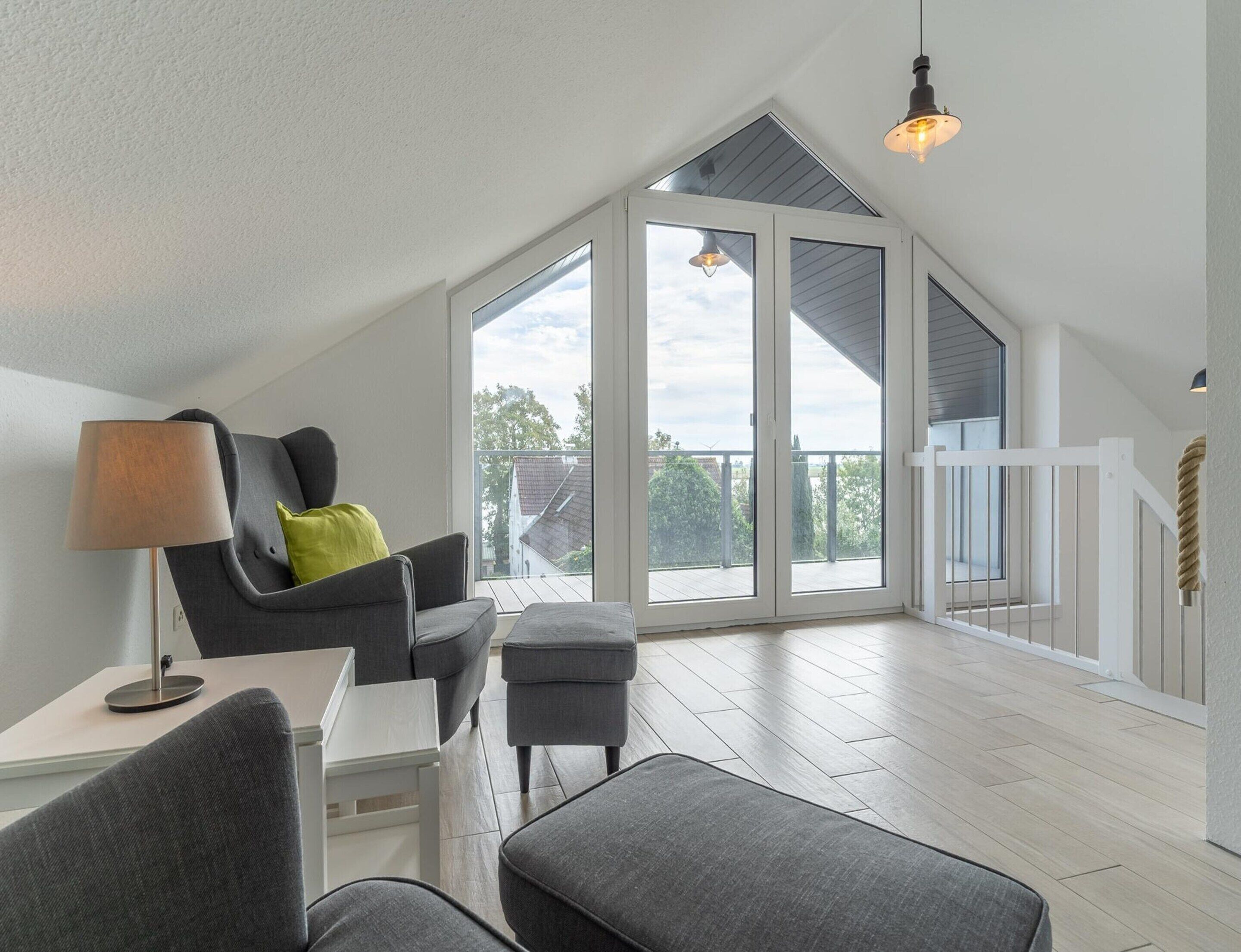 A spacious room with a high ceiling, a large window, and a balcony.