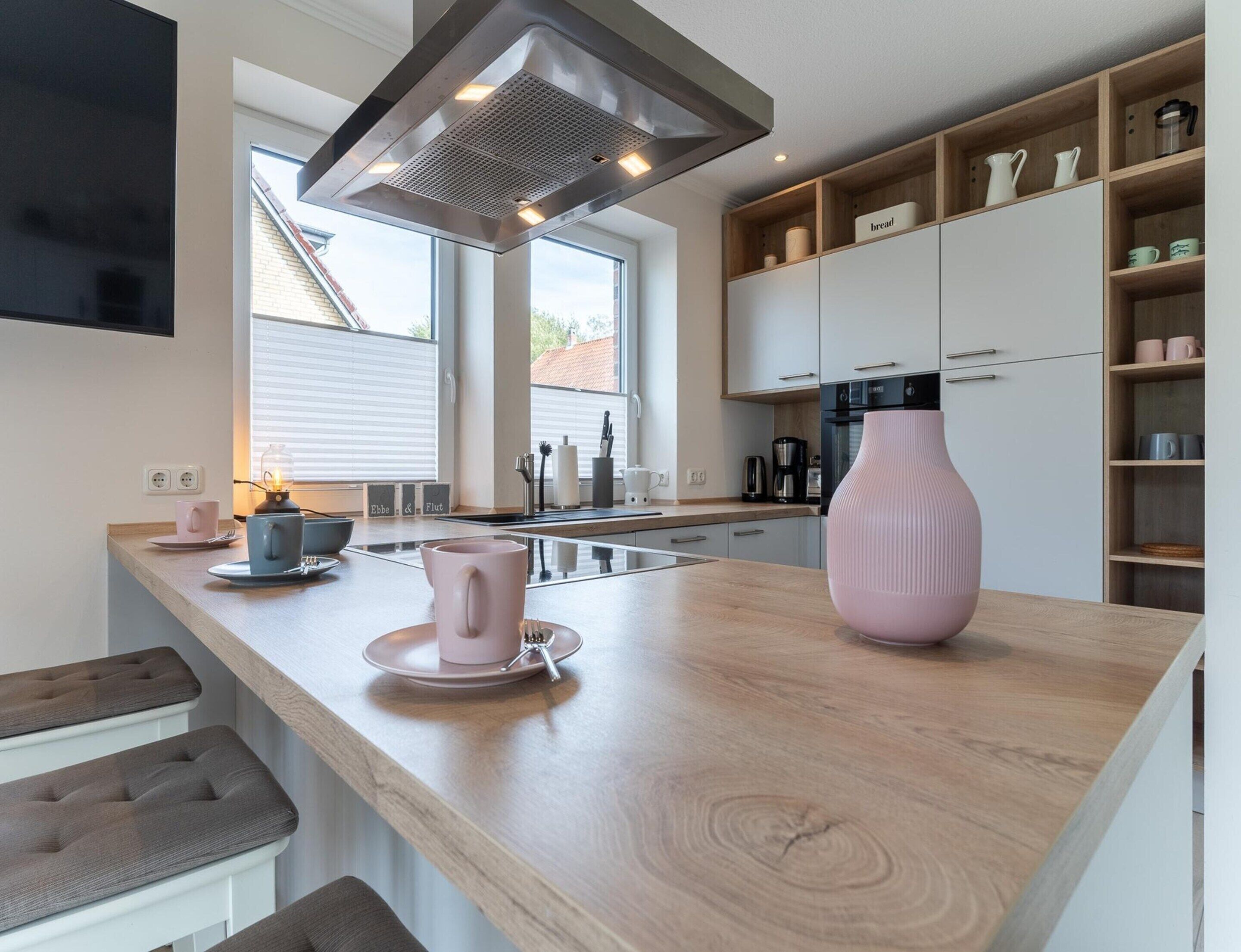 Une cuisine moderne dotée d’un îlot central, d’appareils électroménagers intégrés et d’une grande fenêtre.