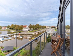 En balkong med utsikt över en flod, båtar och byggnader.