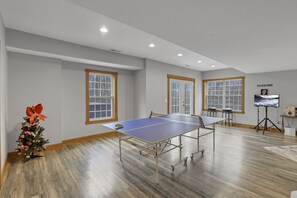 A spacious room with a ping pong table, large windows, and a decorated Christmas tree.