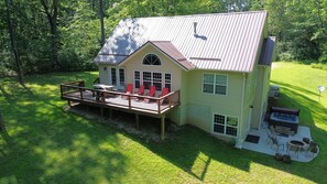 A two-story house with a deck, a fire pit, and a satellite dish.