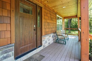 Eine Holztür mit Glasfenster, eine Veranda mit Bank und ein Steinfundament.