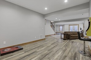 A spacious living room with hardwood flooring, a brown sofa, and a black chair.
