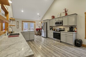 A spacious kitchen with marble countertops, stainless steel appliances, and grey cabinetry. - The Wildrose | Hocking Hills, Hot Tub, Karaoke (Logan)