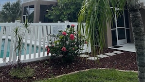 A two-story building with a covered balcony, a pool area with a white fence, and a sign with pool rules. - Gorgeous condo with pool view in walking distance to Siesta Key Beaches (Sarasota)