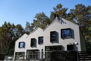 Een modern herenhuis met twee verdiepingen, een puntgevel, grote ramen en een omheinde tuin.