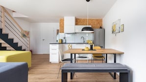 A modern kitchen with white cabinets, a wooden dining table, and a bench. - Holiday Home by Lake Wiselka Near Baltic Beach (gmina Wolin)