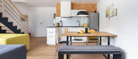 A modern kitchen with white cabinets, a wooden dining table, and a bench.