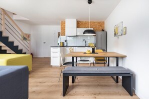 Una cucina moderna con mobili bianchi, un tavolo da pranzo in legno e una panca.