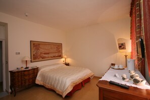 A bedroom with a bed, bedside tables, lamps, a dresser, and decorative items. - Hotel Roma (Scanno)