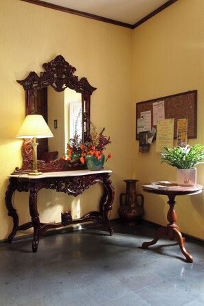 A room with a large ornate mirror, a table with a lamp, and a potted plant. - Hotel Roma (Scanno)