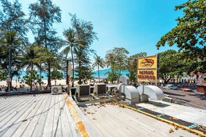 Un restaurante frente a la playa con terraza al aire libre, palmeras y vistas a la playa.