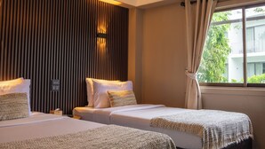 Habitación de hotel con dos camas, una lámpara en el techo, una ventana con cortinas y un panel de control en la pared.