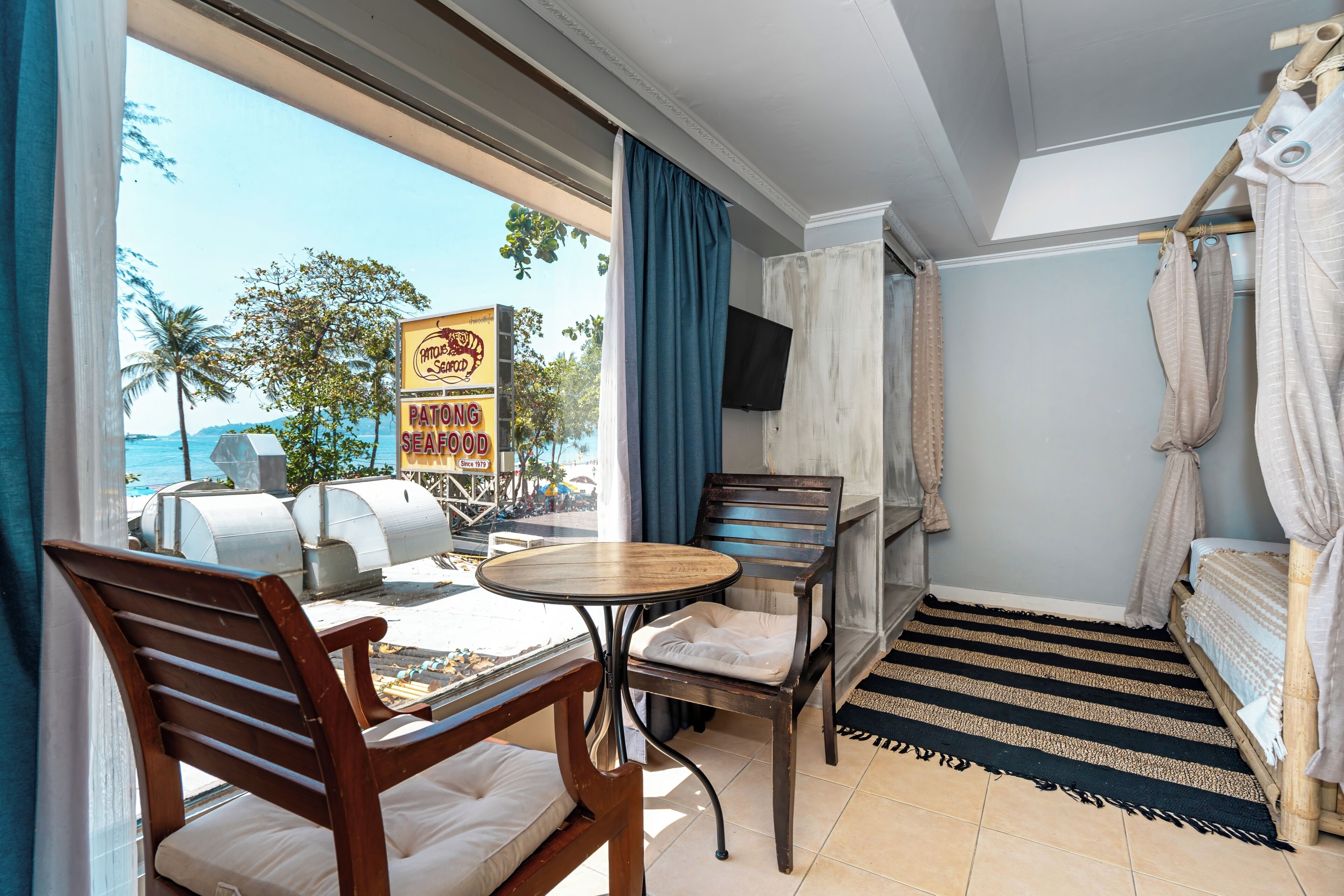 Une chambre avec vue sur la plage, une table, des chaises, un lit et un téléviseur.