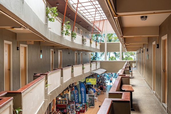 Un espace intérieur à plusieurs niveaux, doté de balcons, d’une allée centrale et d’une zone commerciale.