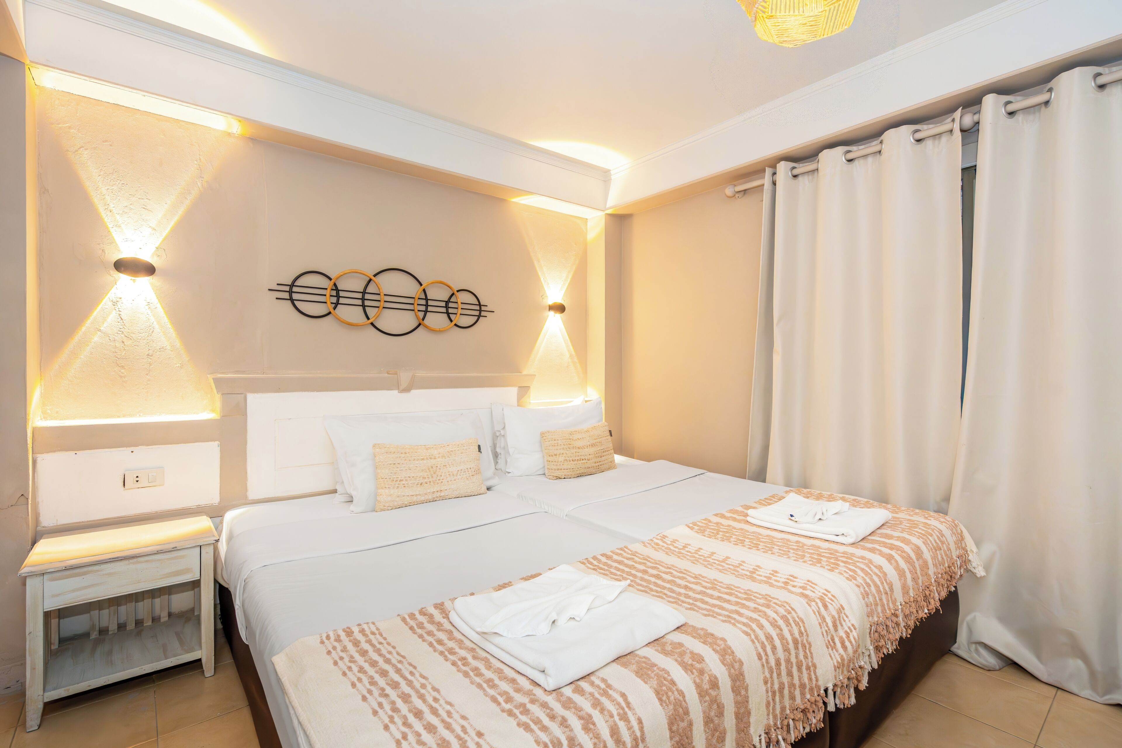 Une chambre d’hôtel avec un grand lit, des lampes de chevet, une œuvre d’art murale et un rideau.
