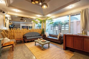 A modern living room with a sofa, a coffee table, and a wooden cabinet. - The Taksim Bangla Beach Hotel - Adults Only  (Patong)
