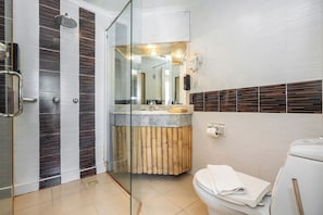 Une salle de bain moderne dotée d’une douche à parois de verre, d’un meuble-lavabo avec un plan de travail en marbre et de toilettes agrémentées d’un élément décoratif en bambou.