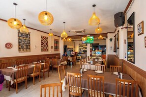 A restaurant with wooden tables and chairs, hanging wicker lamps, and patterned wall decorations. - The Taksim Bangla Beach Hotel - Adults Only  (Patong)