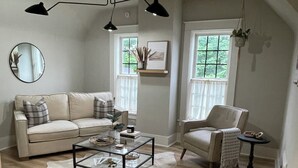 Una sala de estar con sofá, sillón, mesa de centro y lámpara colgante.