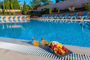 A swimming pool with lounge chairs and a fruit platter with drinks. - Townhouse Ocean Joy (Albufeira)