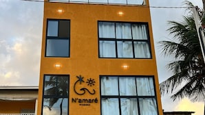 Un edificio de varios pisos con fachada amarilla, ventanas grandes y un cartel que dice "N'amare Pousada".